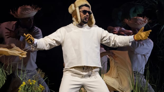 Bad Bunny performs during the final concert of his summer residency in his homeland at the Coliseo de Puerto Rico Jose Miguel Agrelot, in San Juan, Puerto Rico, Saturday, Sept. 20, 2025. Singer wearing white and a fur hat and sunglasses sings into a remote microphone on stage