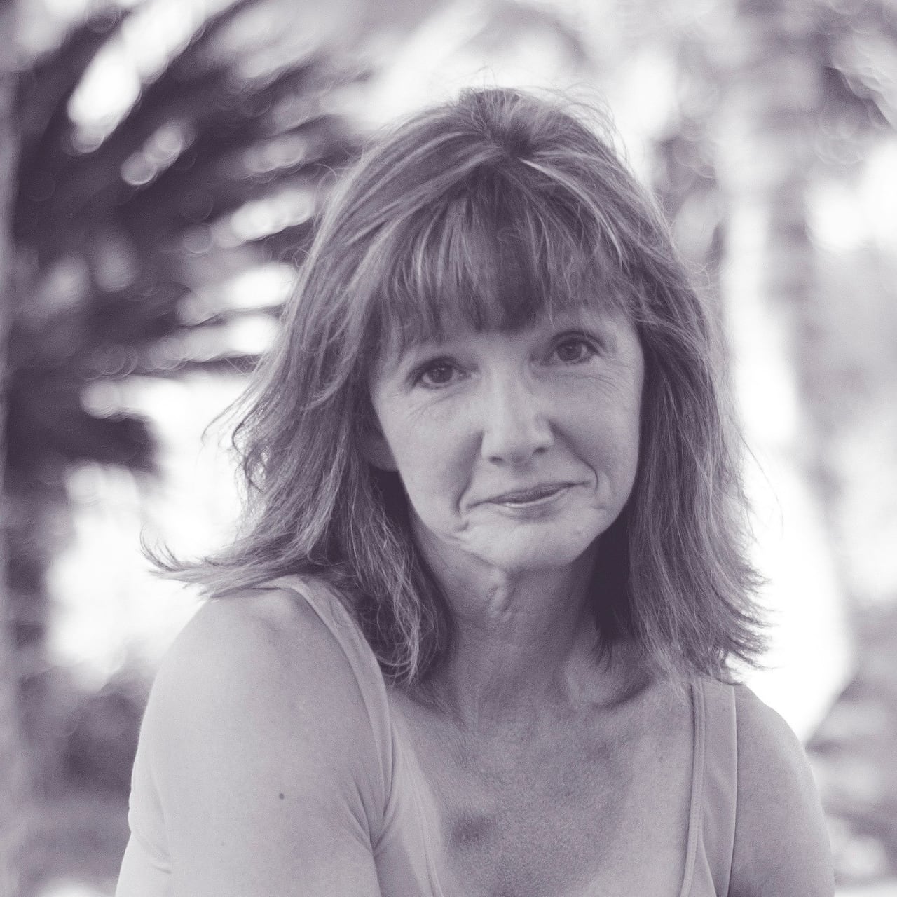 A achromatic and achromatic photograph of a pistillate wearing a vessel apical and looking astatine the camera.