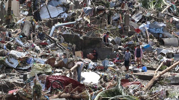 People walk through rubble and destroyed homes