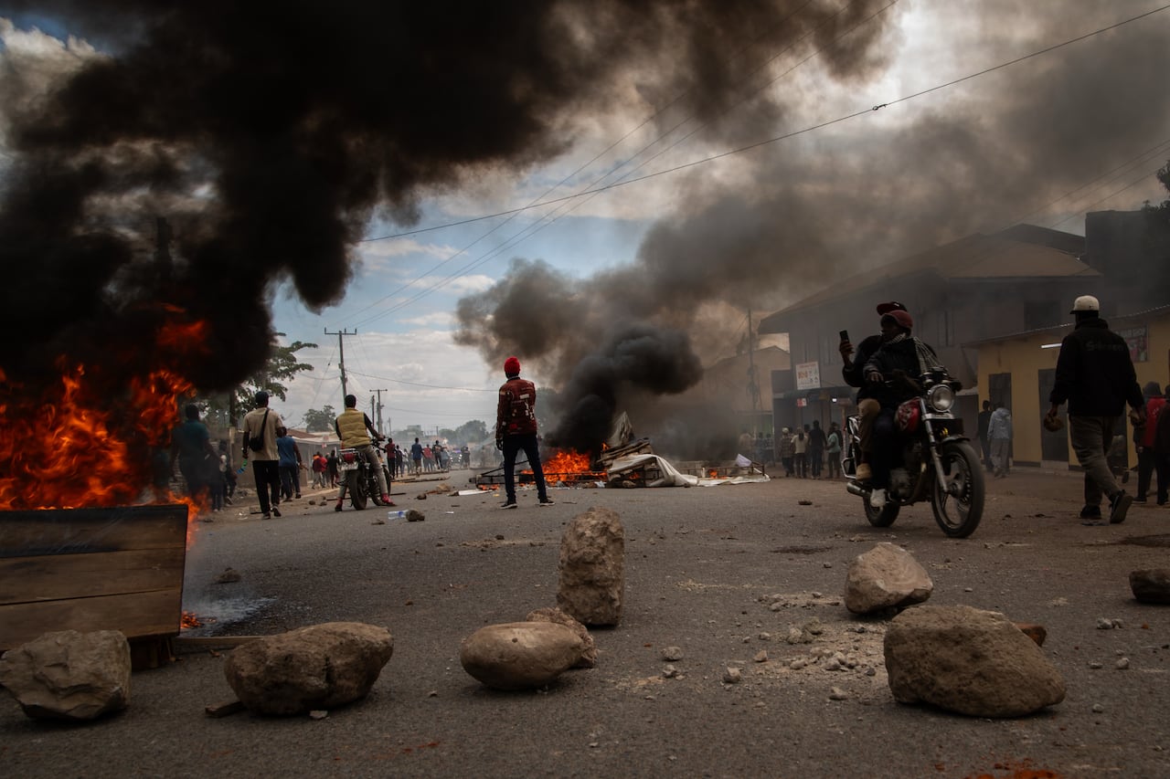 Smoke billows from fires amid protests in Tanzania, people standing around