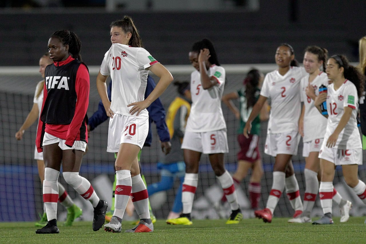 Soccer players representing Canada leave the field after a loss.