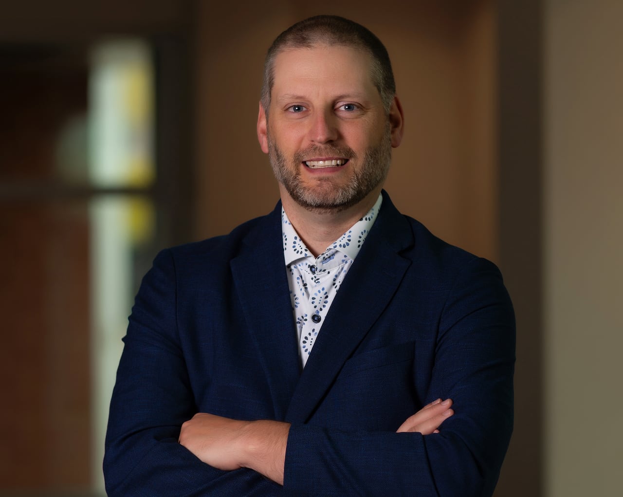 A man standing and smiling with his arms crossed.