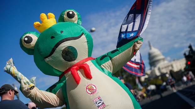 WASHINGTON, DC - OCTOBER 18: A protestor wearing a frog costume, which has emerged from protests in Portland as a symbol of the opposition to ICE, and a Subway sandwich, which became popular in D.C. as a symbol of resistance, during the second "No Kings" protest on October 18, 2025 in Washington, DC. Organizers expect millions to participate in cities and towns across the nation for the second "No Kings" protest to denounce the Trump administration. (Photo by Nathan Howard/Getty Images) Aperson in a giant inflatable frog costume, with a crown on its head, a protest flag in one hand and and a Quiznos sub in the other. On its stomach are stickers that read: