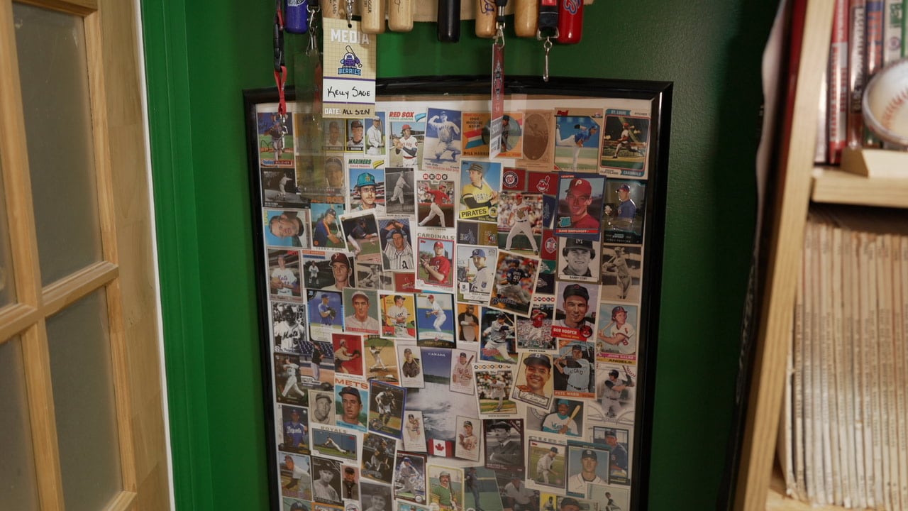 A display case of baseball cards from Canadians who have played in the major leagues hangs on a green wall in the corner of a room next to a door.
