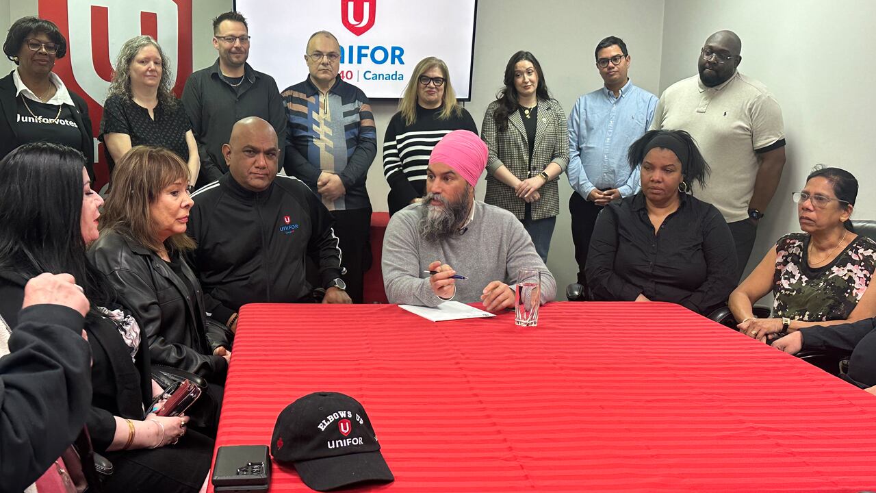 A antheral   successful  a pinkish  turban sits astatine  a array  with a reddish  tablecloth, surrounded by different   people.