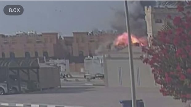 Grainy CCTV footage of an explosive plume of fire beginning to billow out from a building.