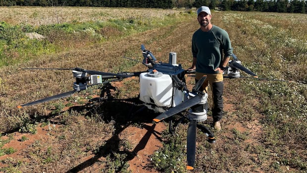 Drones are giving P.E.I. farmers high-flying advantage, including early seeding from the sky A man stands in a field holding a large drone
