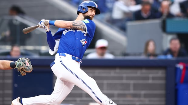 A man in a baseball uniform swings a bat