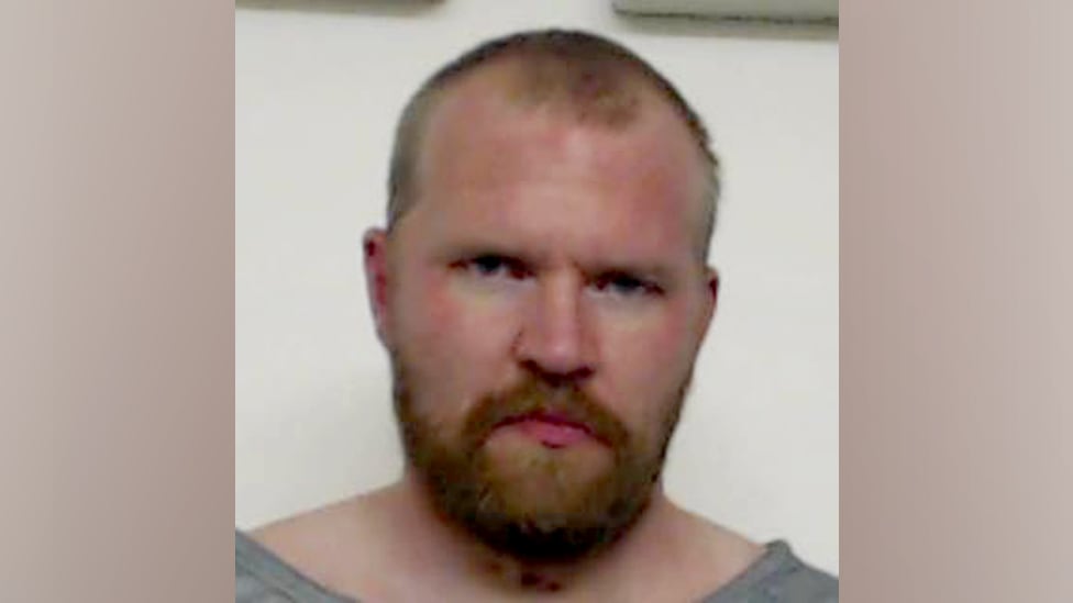 The man is seen on the shoulders up. You have a beard and the haircut clothed close. He doesn't smile.