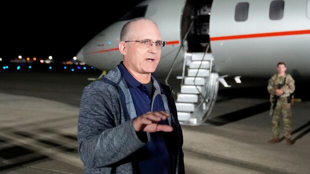 Paul Whelan speaks at Andrews Air Force Base, Md., following his release as part of a 24-person prisoner swap between Russia and the United States, Thursday, Aug. 1, 2024. a man in glasses speaks in front of a plane