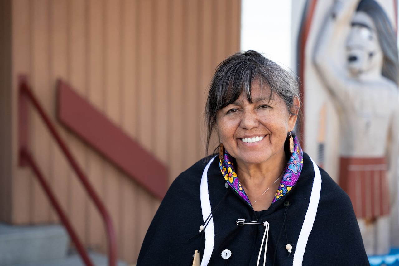 A woman wearing a purple and black sweater smiles at the camera.