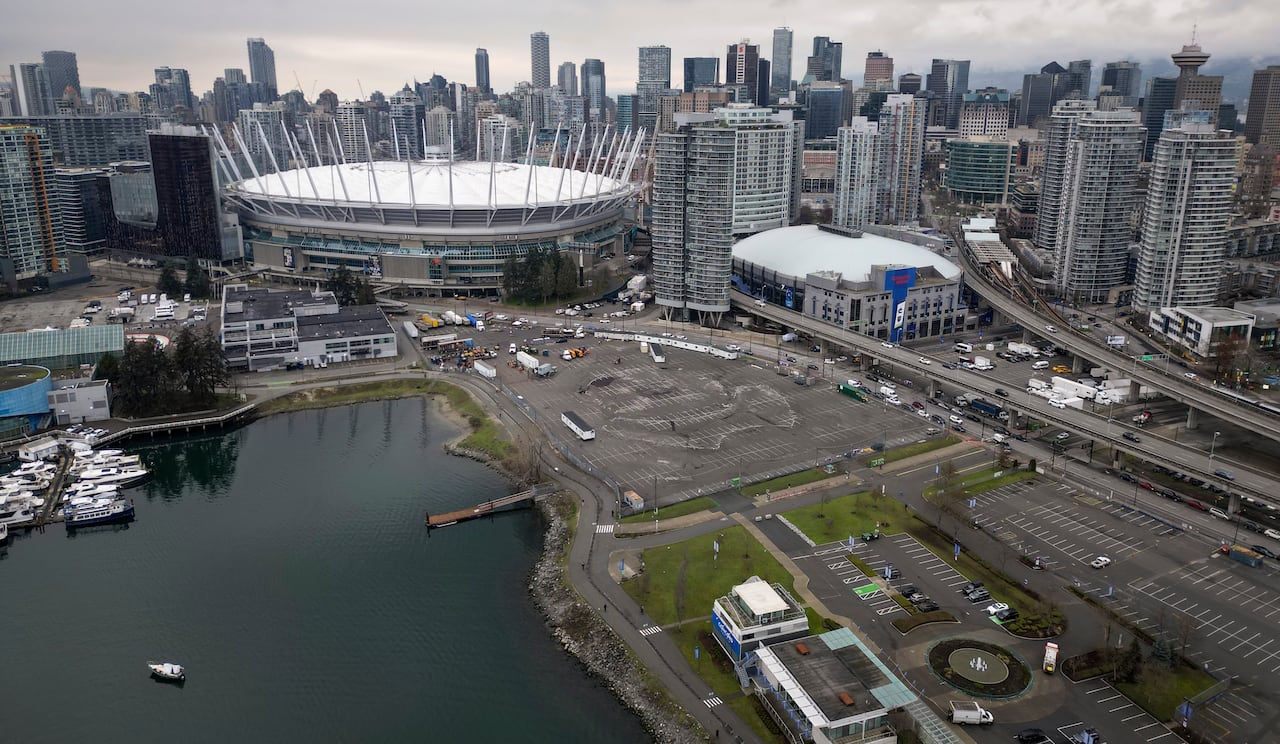 A large stadium and hockey arena are visible next to the pond, parking lot and city center skyline.