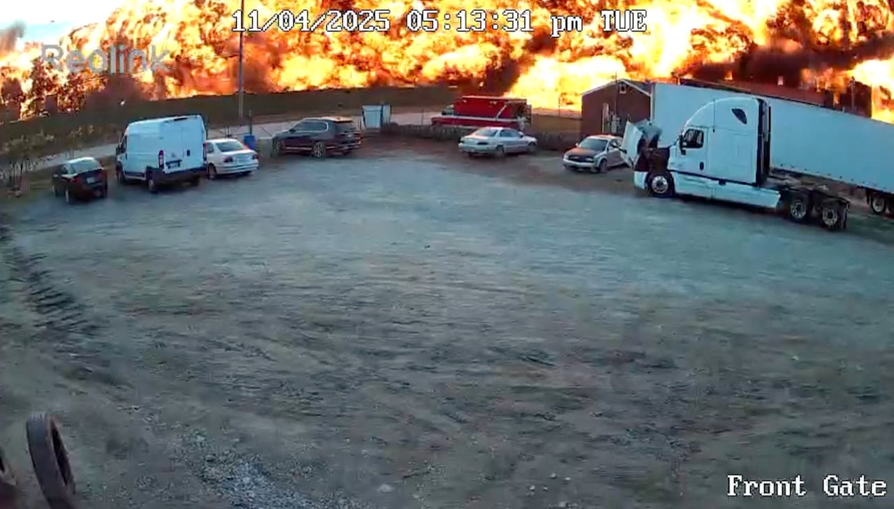 A parking lot with a wall of flame and fire behind it