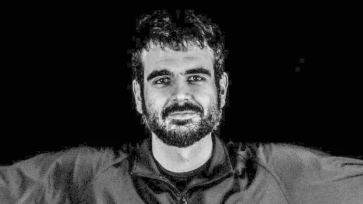 A black and white photo of a man with a beard and short hair smiling.