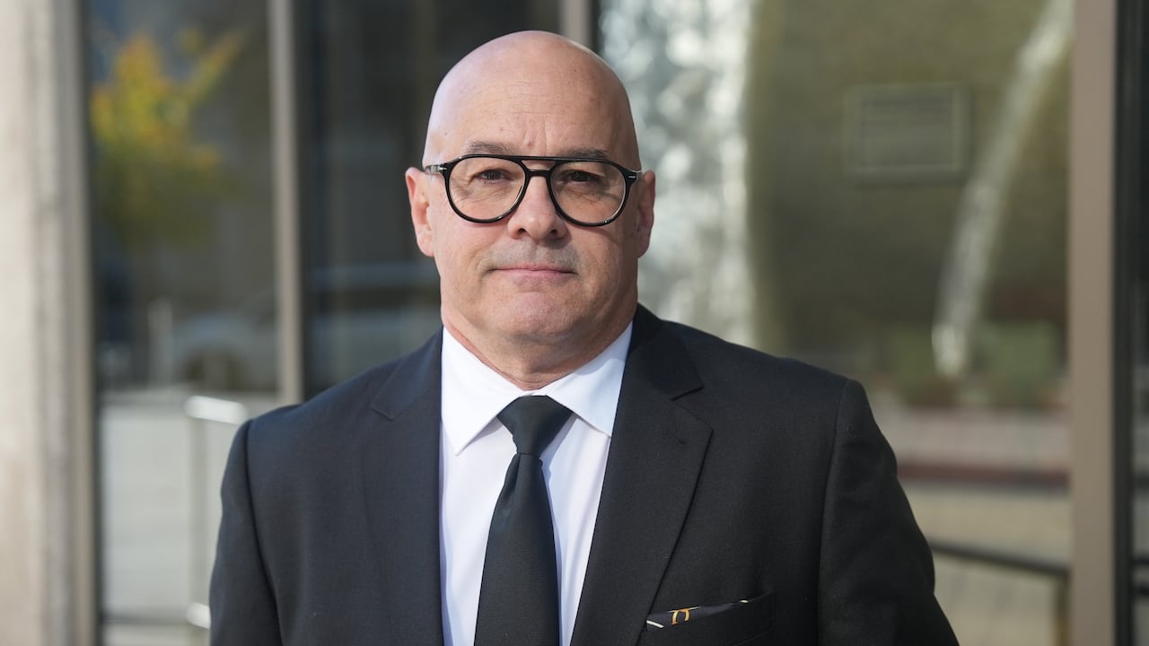 A man in glasses stands outside a courthouse.