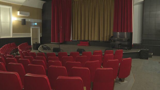 Rows of seats curve around the stage at the Souris Show Hall in northeastern P.E.I. Five rows of red theatre seats curve around a low stage in a theatre.