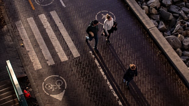 Three people walk along a path, pictured from above