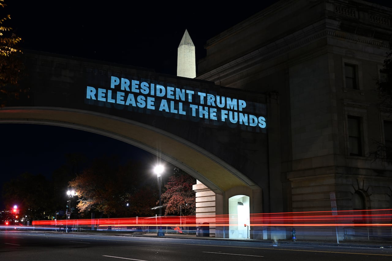 A video message is projected on a bridge, which says 'President Trump release all the funds.'