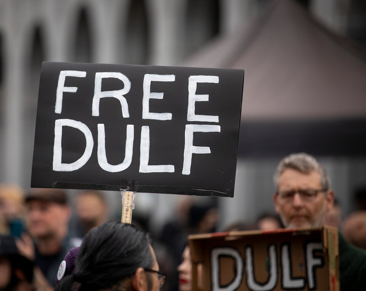 A sign says 'Free DULF' at a rally.