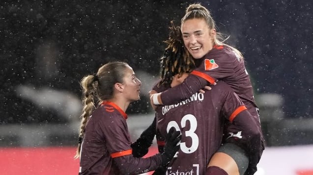Women's soccer players celebrate a goal.