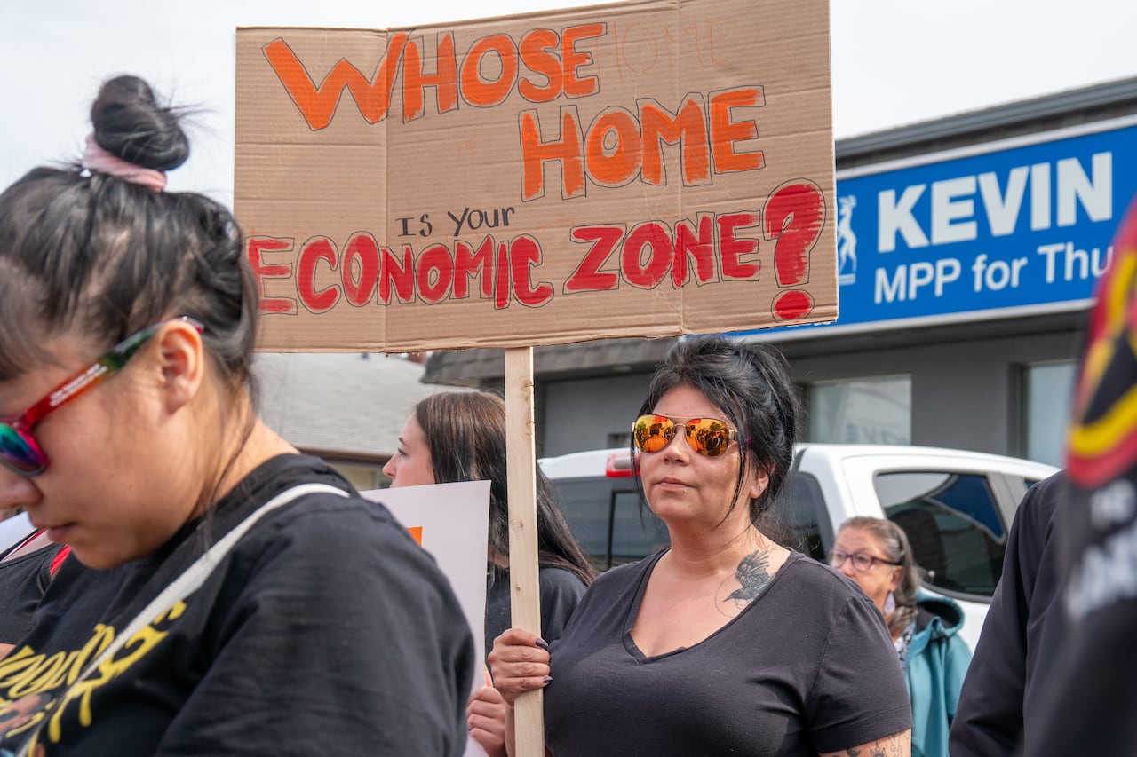A person is seen holding a sign that says "Whose home is your economic zone?"