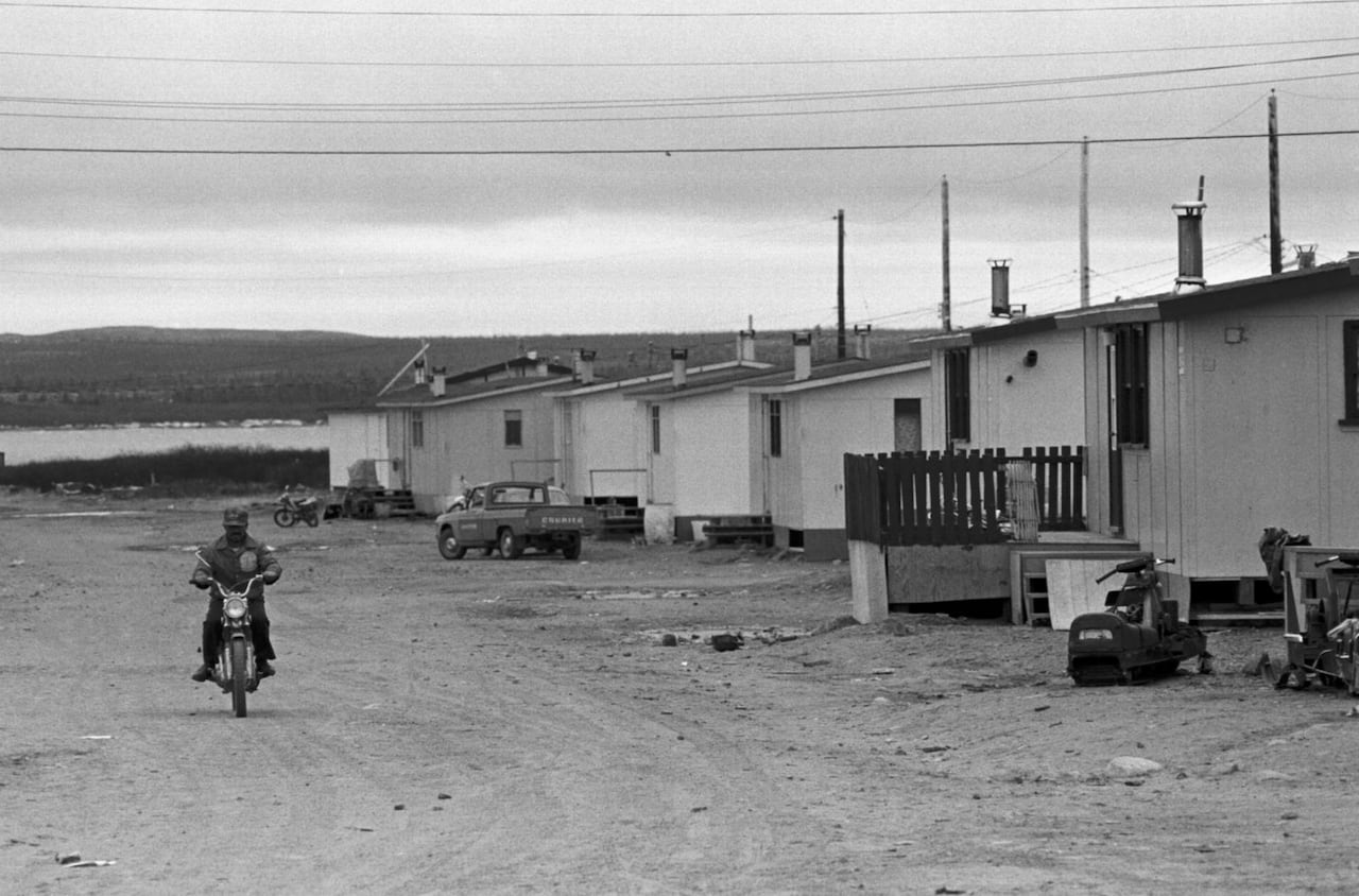 man on motorized bike drives past some houses