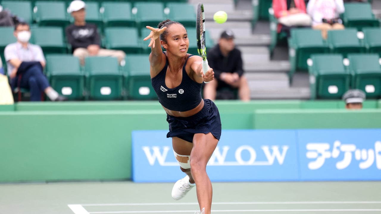 A women's tennis player lunges to make a shot during a match on a hard court.