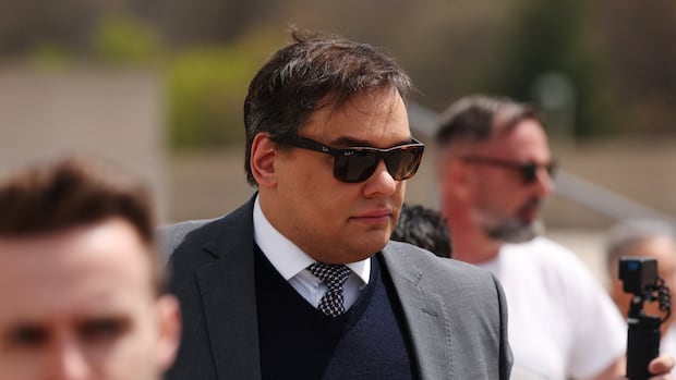 A man in a suit and sunglasses is pictured.