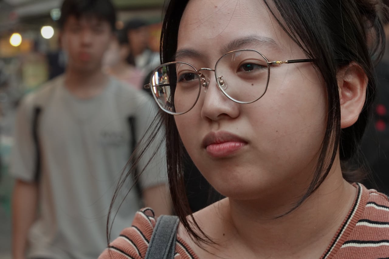 A young woman with black hair wears glasses.