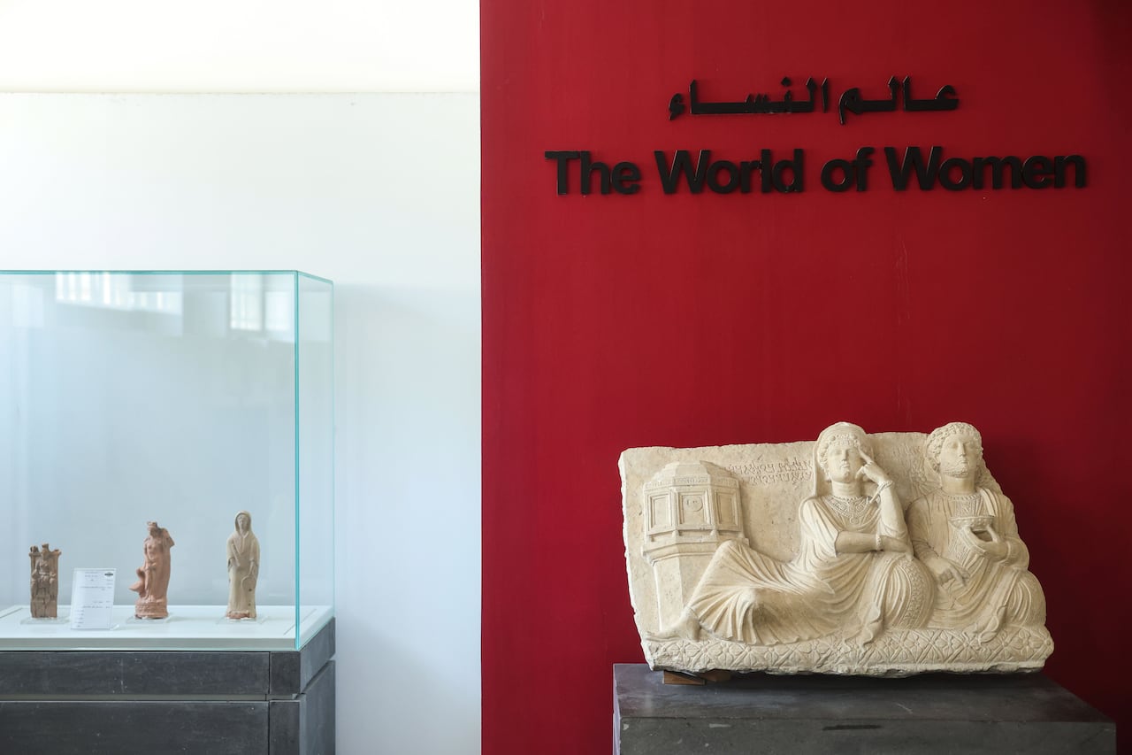 Ancient sculptures are displayed in a section titled "The World of Women" at a museum.