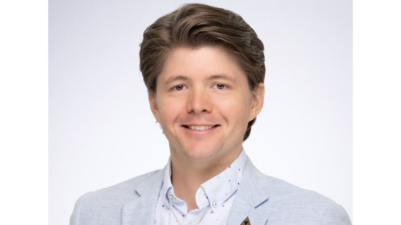 A man with brown short hair smiles at the camera.