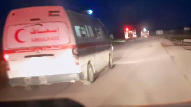 Dark night sky. Ambulances on a dirt road with lights on. 