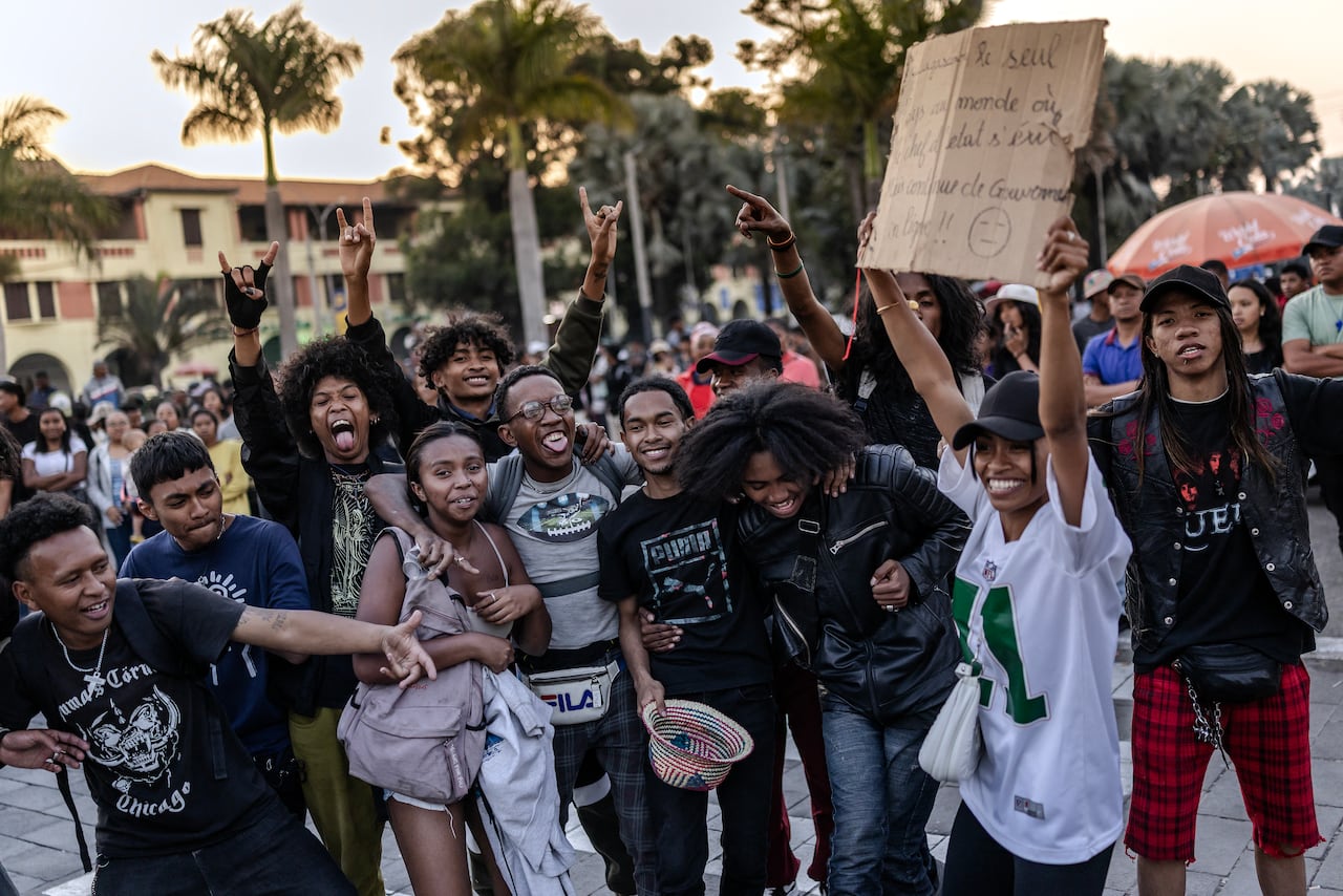 Several young people, black have worked and both men and women, smile and raise their arms in the outdoor photo.