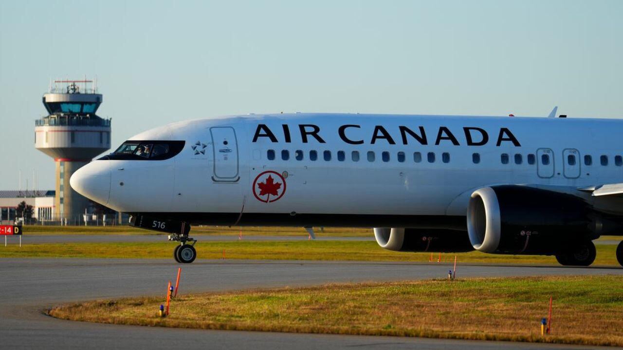 A plane with the text 'Air Canada' on it sits on a runway.