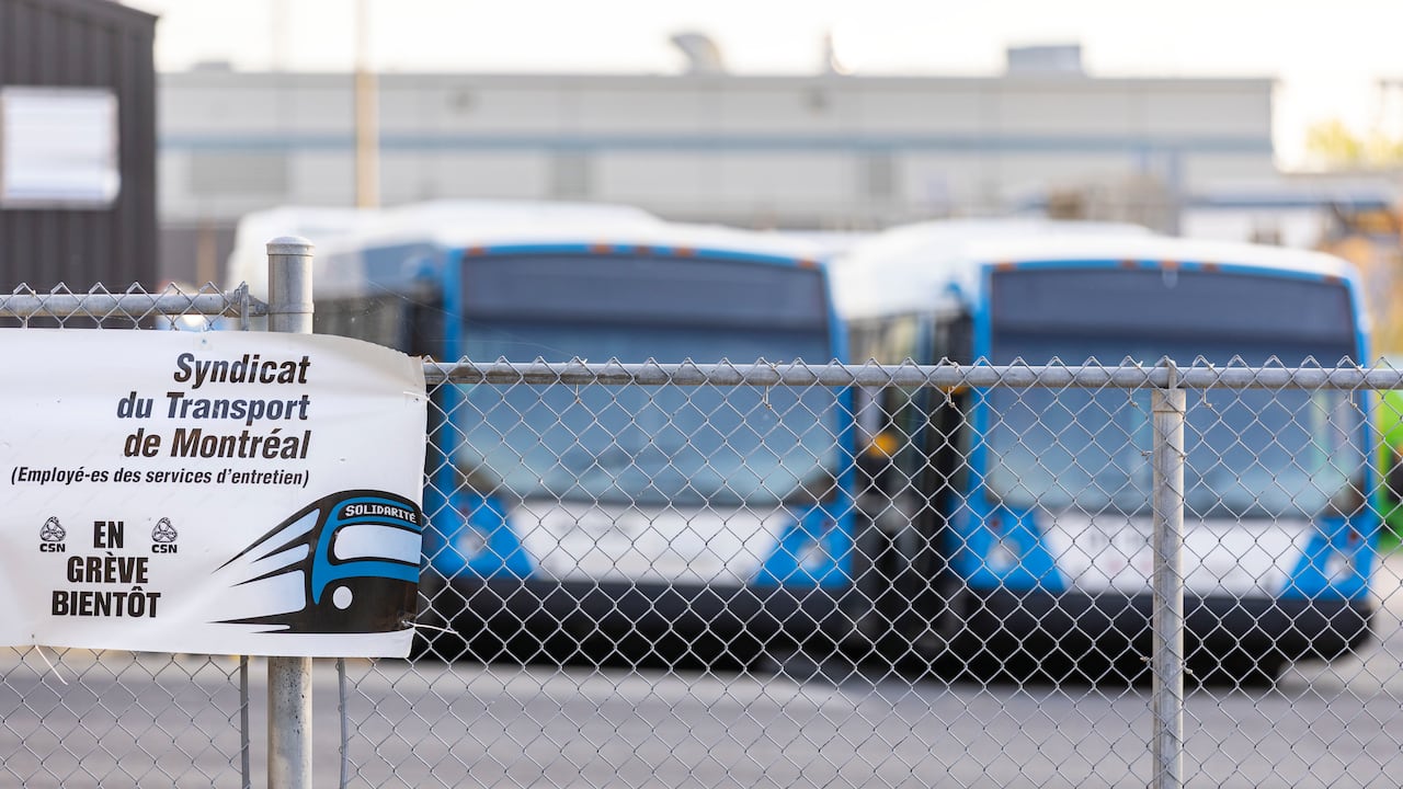 Buses are parked successful a lot. A obstruction is successful the foreground and the buses are blurred successful the background.