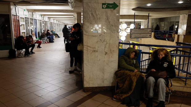 People in winter coats sit and sleep in a Metro station