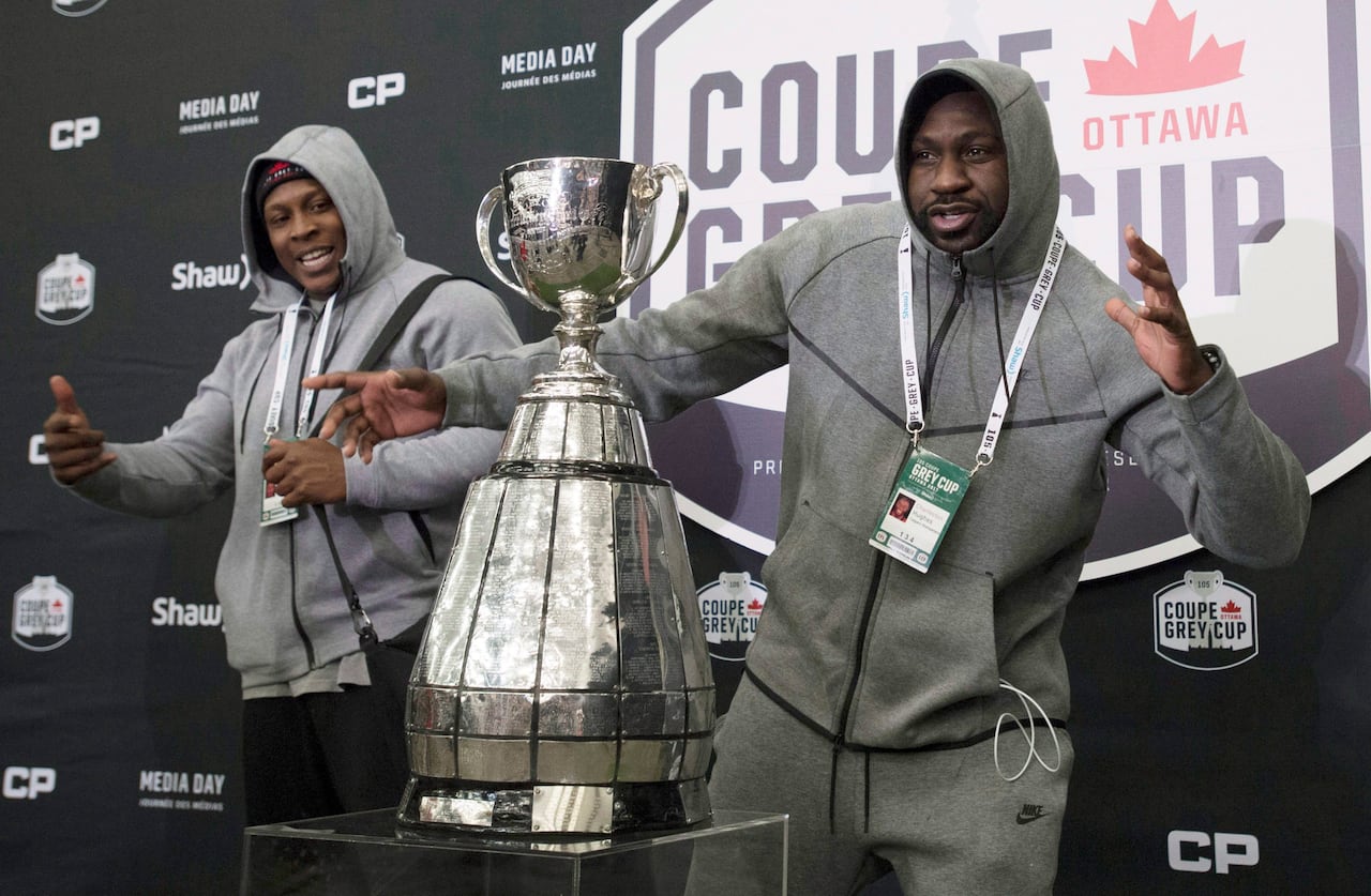 Two football players pose with the Grey Cup.