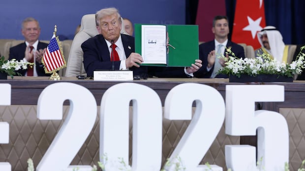 Donald Trump stands in front of podium, mouth open to signal speech
