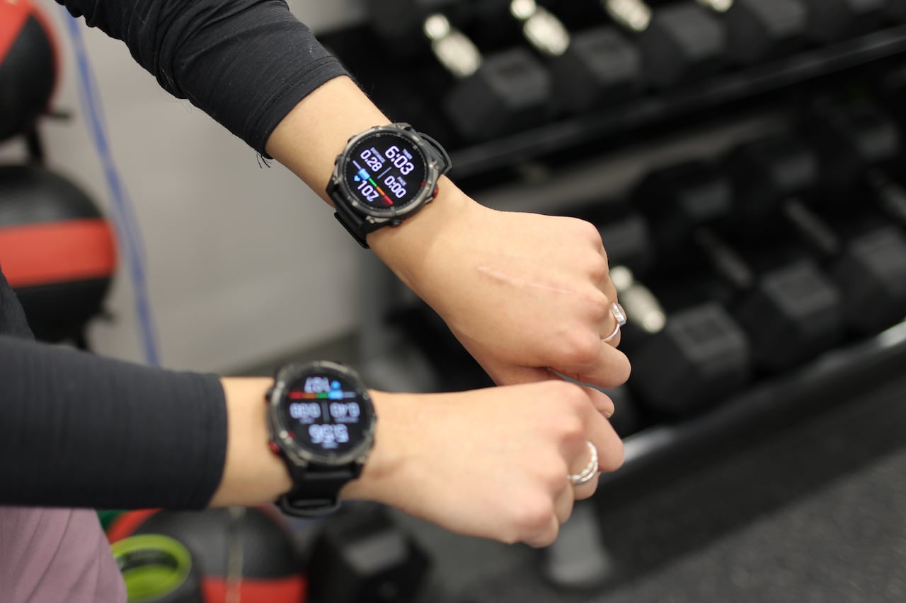 A woman shows off two fitness watches, one on each hand.
