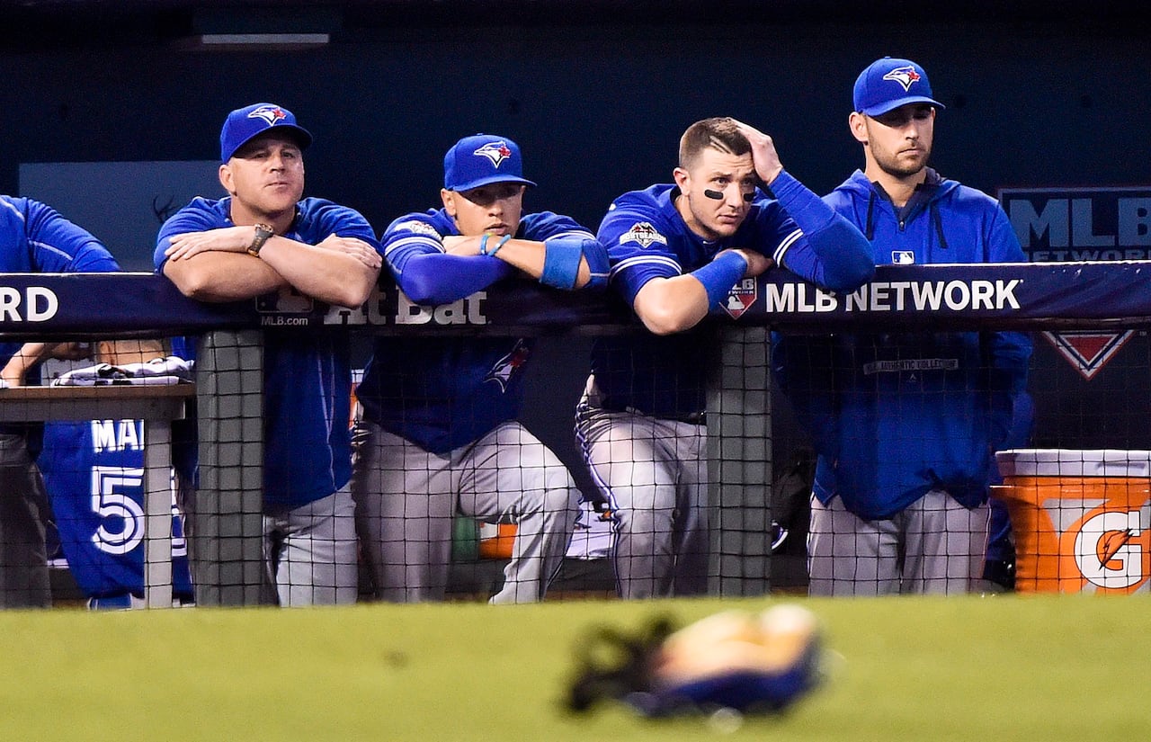 Several baseball players looking out from a standing position inside a dugout