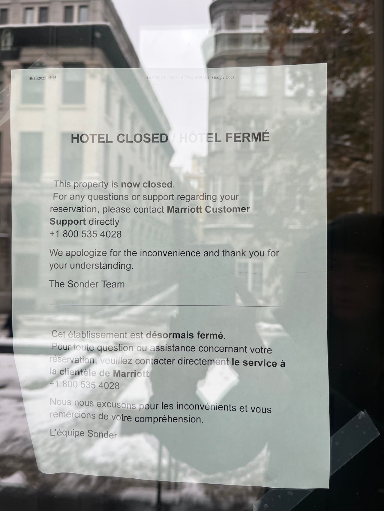 A letter visible through a window informing people that a building is closed, stuck to the inside of the glass