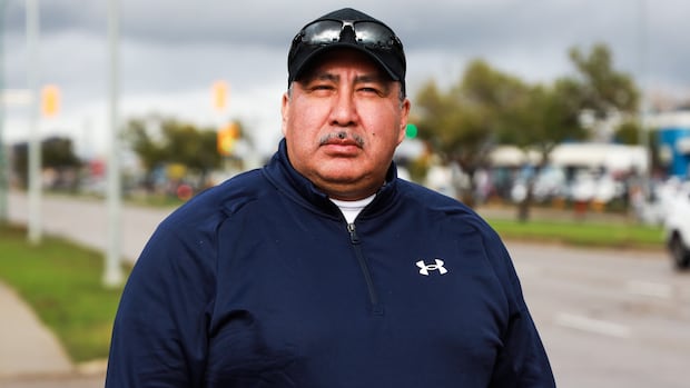 A man in a black baseball cap and sweatshirt looks forward.