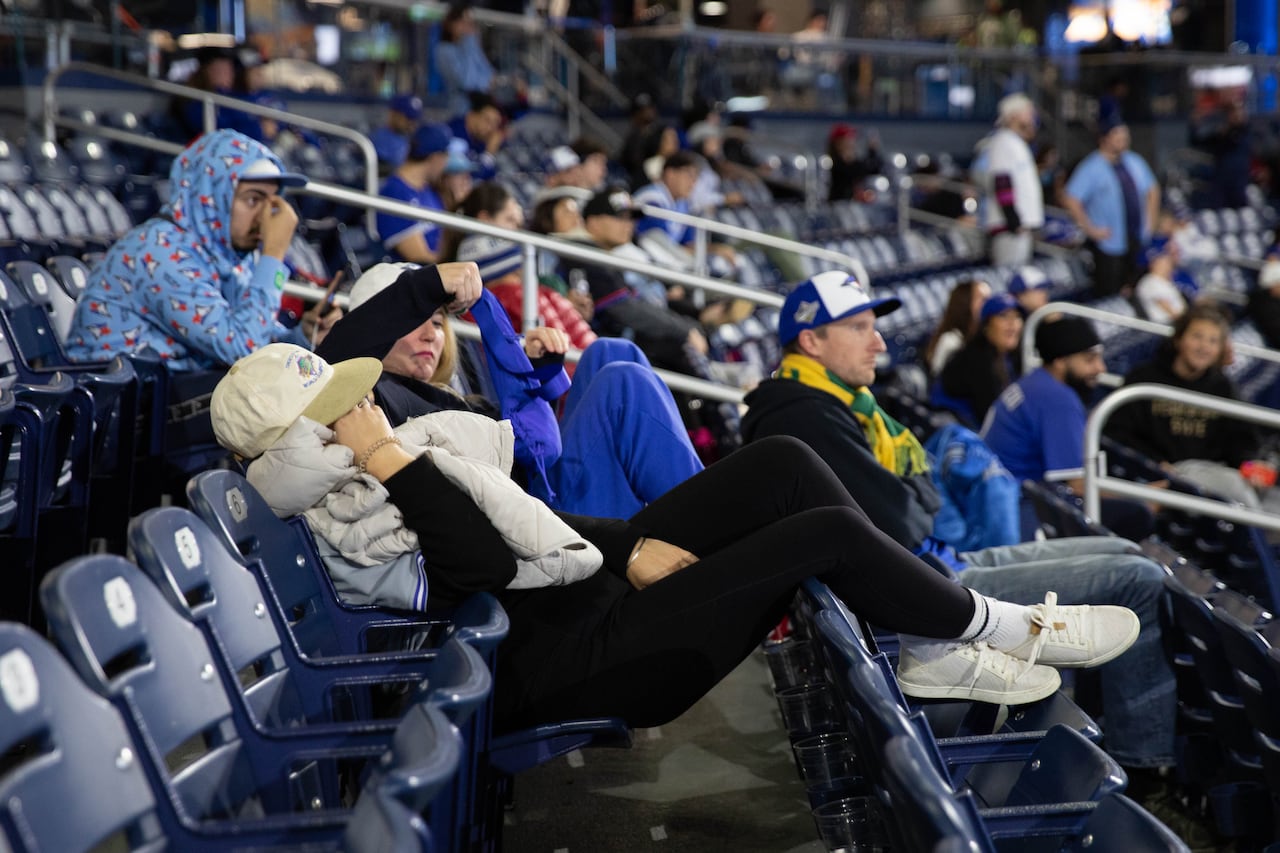 a woman in black leggings reclines on seats in a sports arena