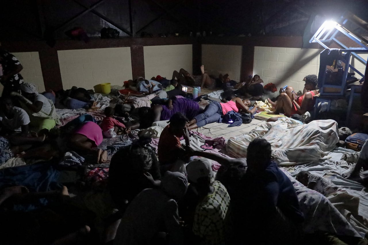 रात्रीच्या दृश्यात डझनभर अंधारलेले लोक एका छोट्या घरातील जागेत घुसलेले दाखवतात.