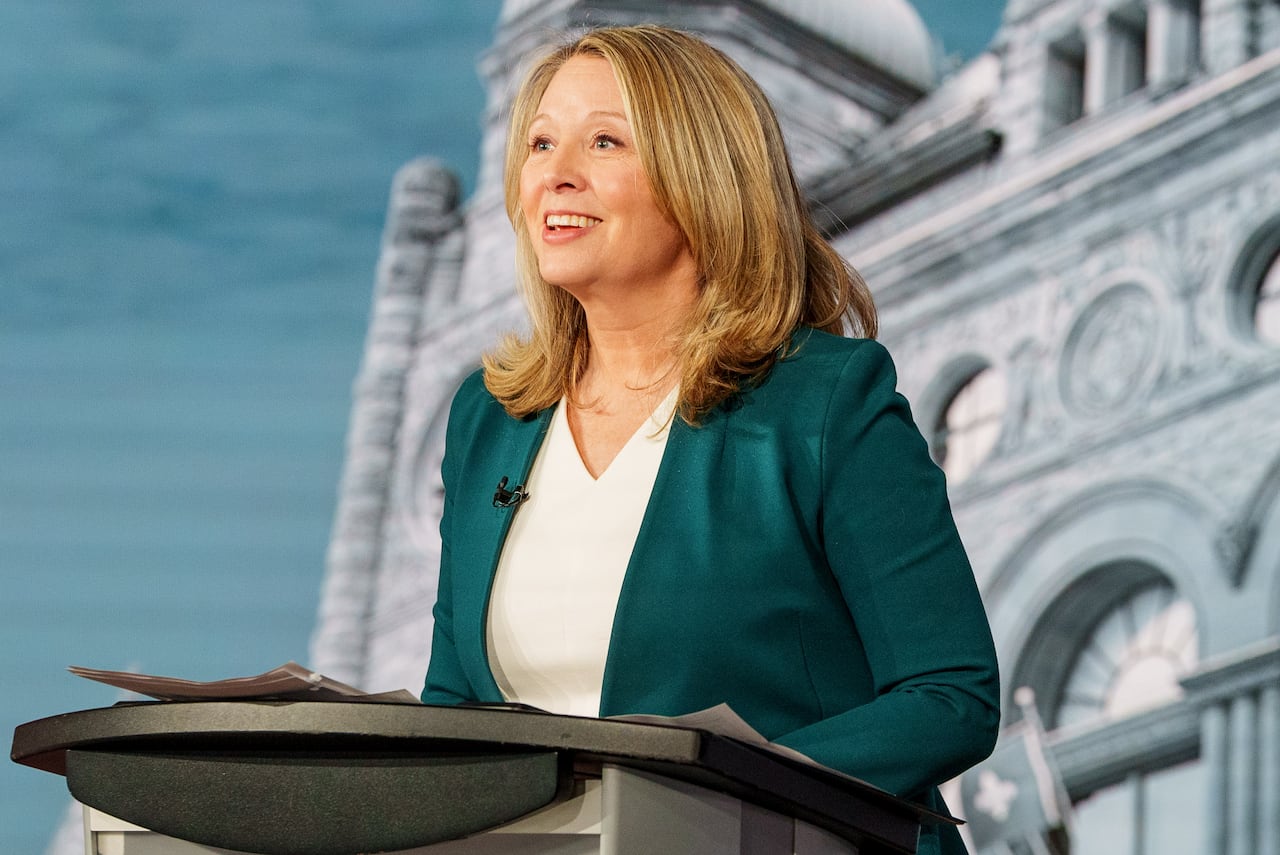 A woman leans forward while standing at a podium.