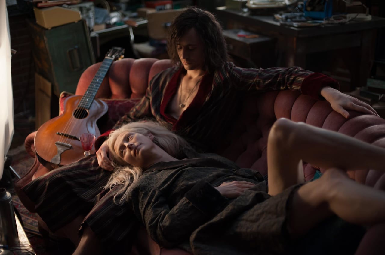A man and woman lounging on a couch. She's resting her head in his lap.