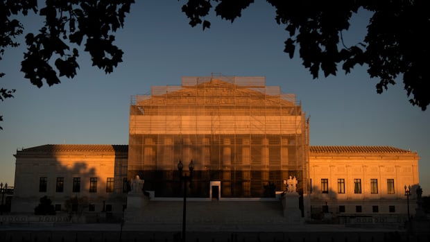 A wide shot of a grey marble building is shown in soft sunlight.
