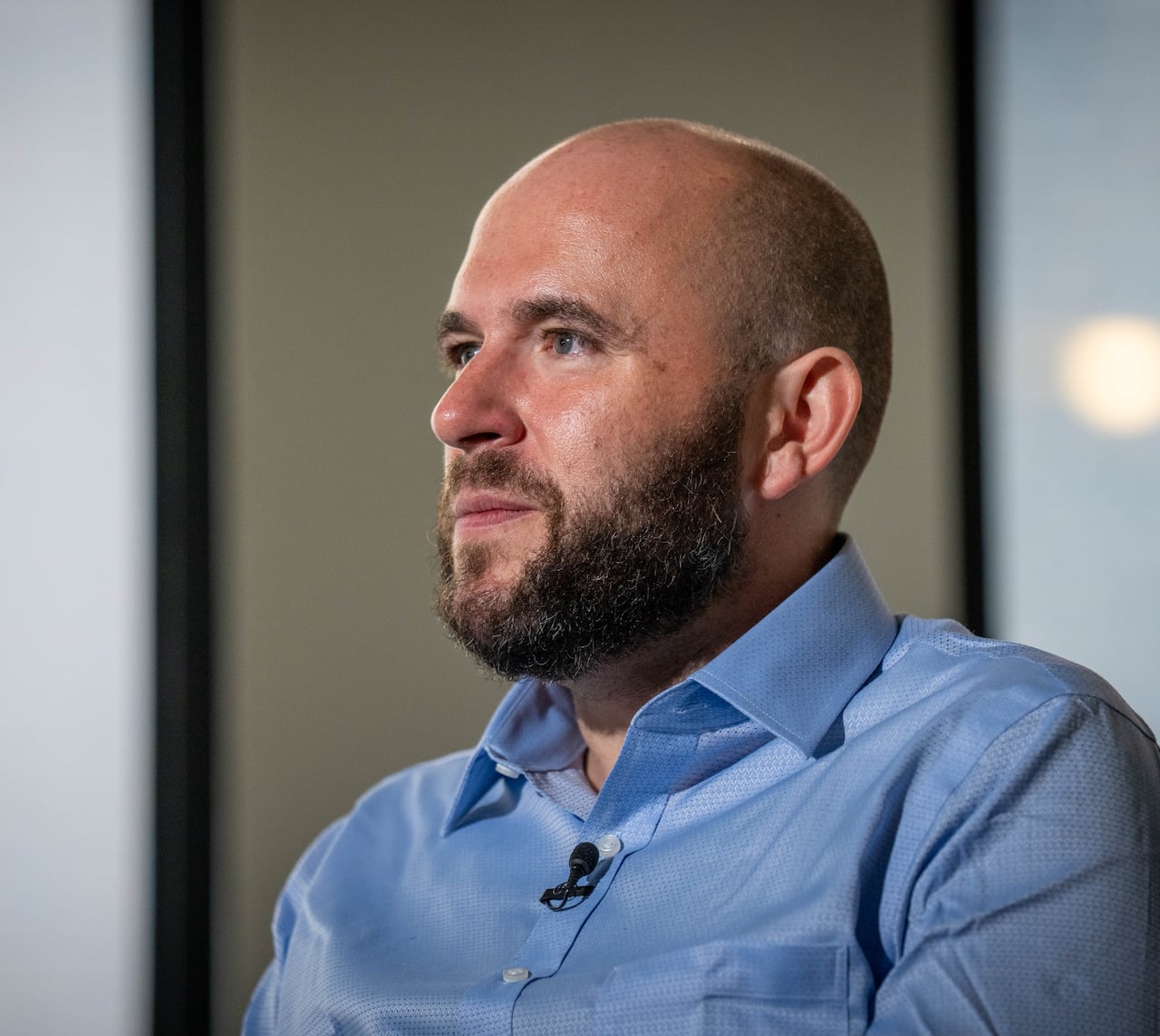 A white man with a short-cropped beard wearing a blue collared shirt