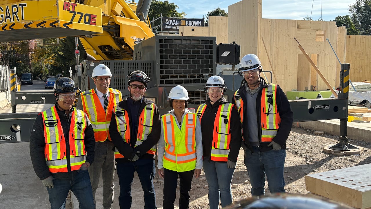 People in construction vests standing in construction site, smiling for photo