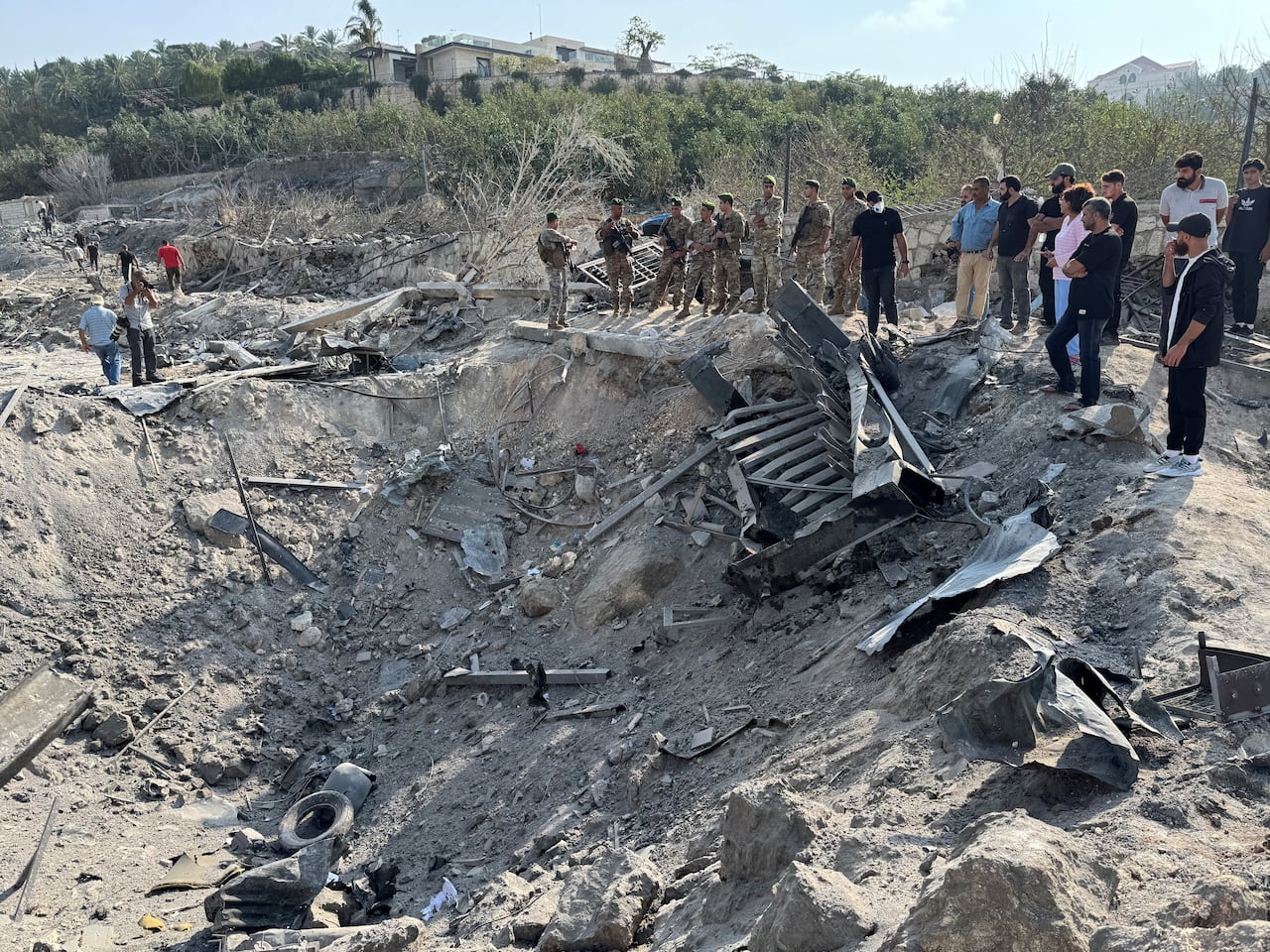 Lebanese people and army members gather at a damaged site.